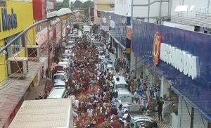 Vista elevada de rua de comércio popular com lojas dos dois lados e grande fluxo de pedestres