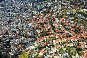 Vista aérea de bairro brasileiro com contraste entre torres residenciais verticais e casas de telhado baixo